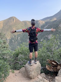 a man standing on top of a rock with his arms outstretched